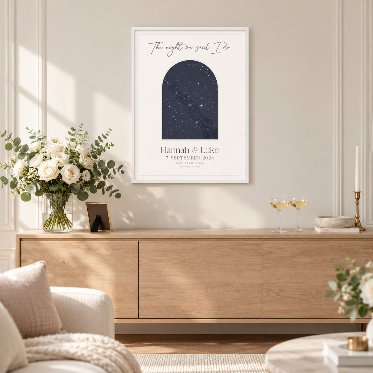 Wedding star map print framed above a sideboard with white roses